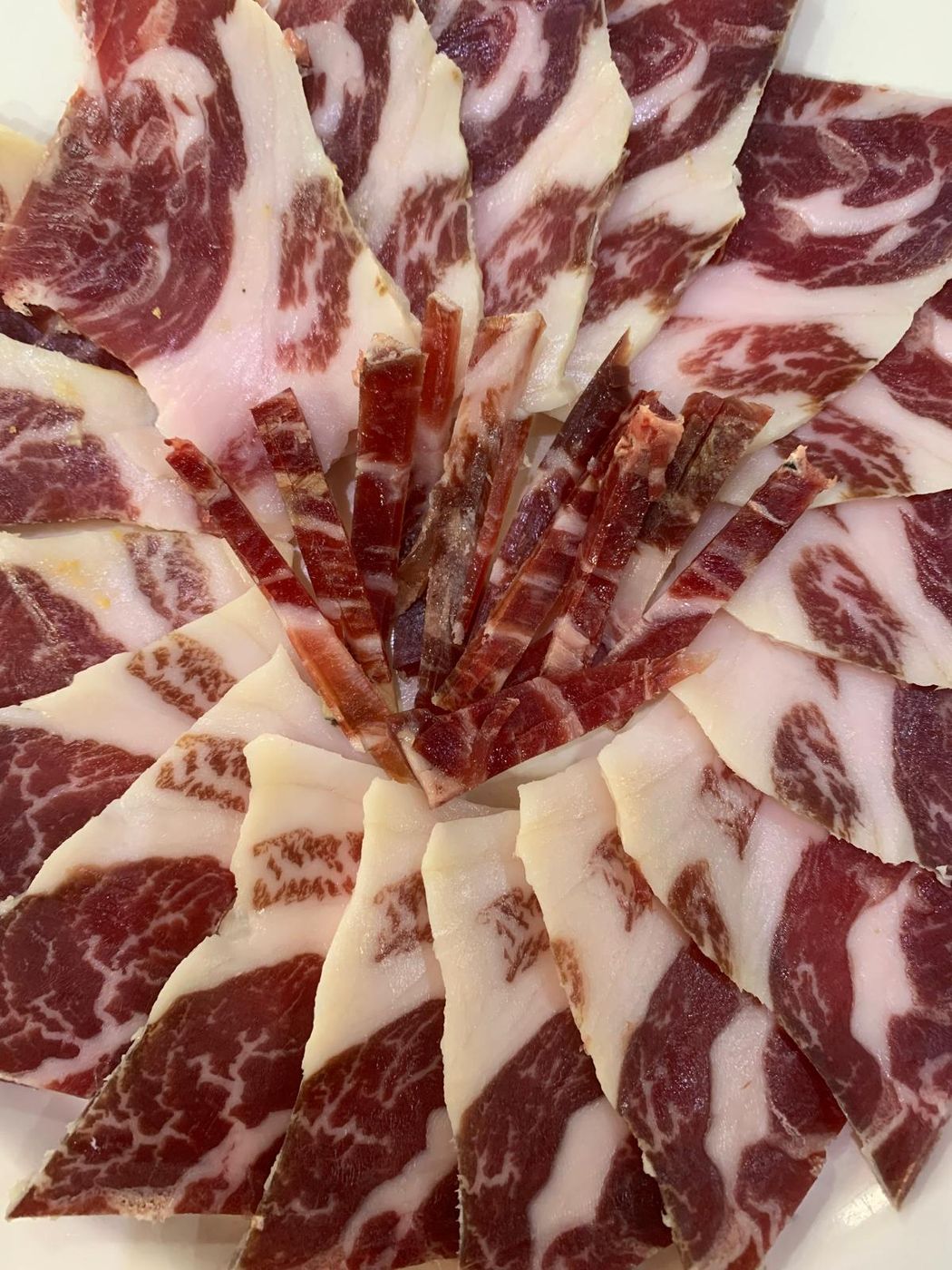 Lonchas de jamón ibérico de bellota dispuestas en estrella mostrando el veteado