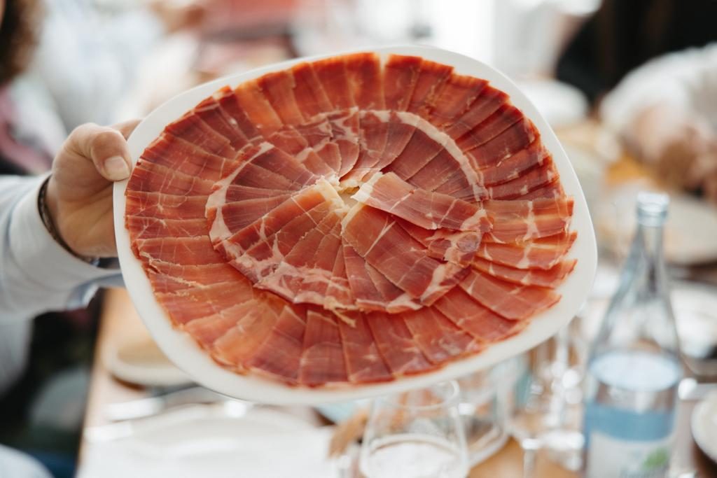 Bandeja enorme de jamón ibérico recién cortado y presentado en una mesa de evento privado