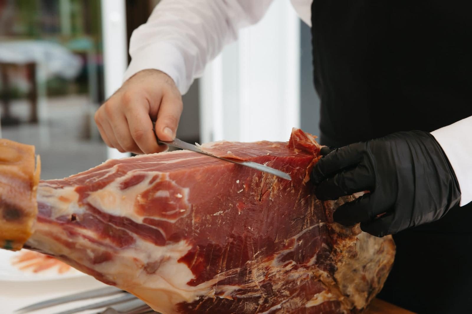 Primer plano del corte de un jamón ibérico con cuchillo jamonero profesional