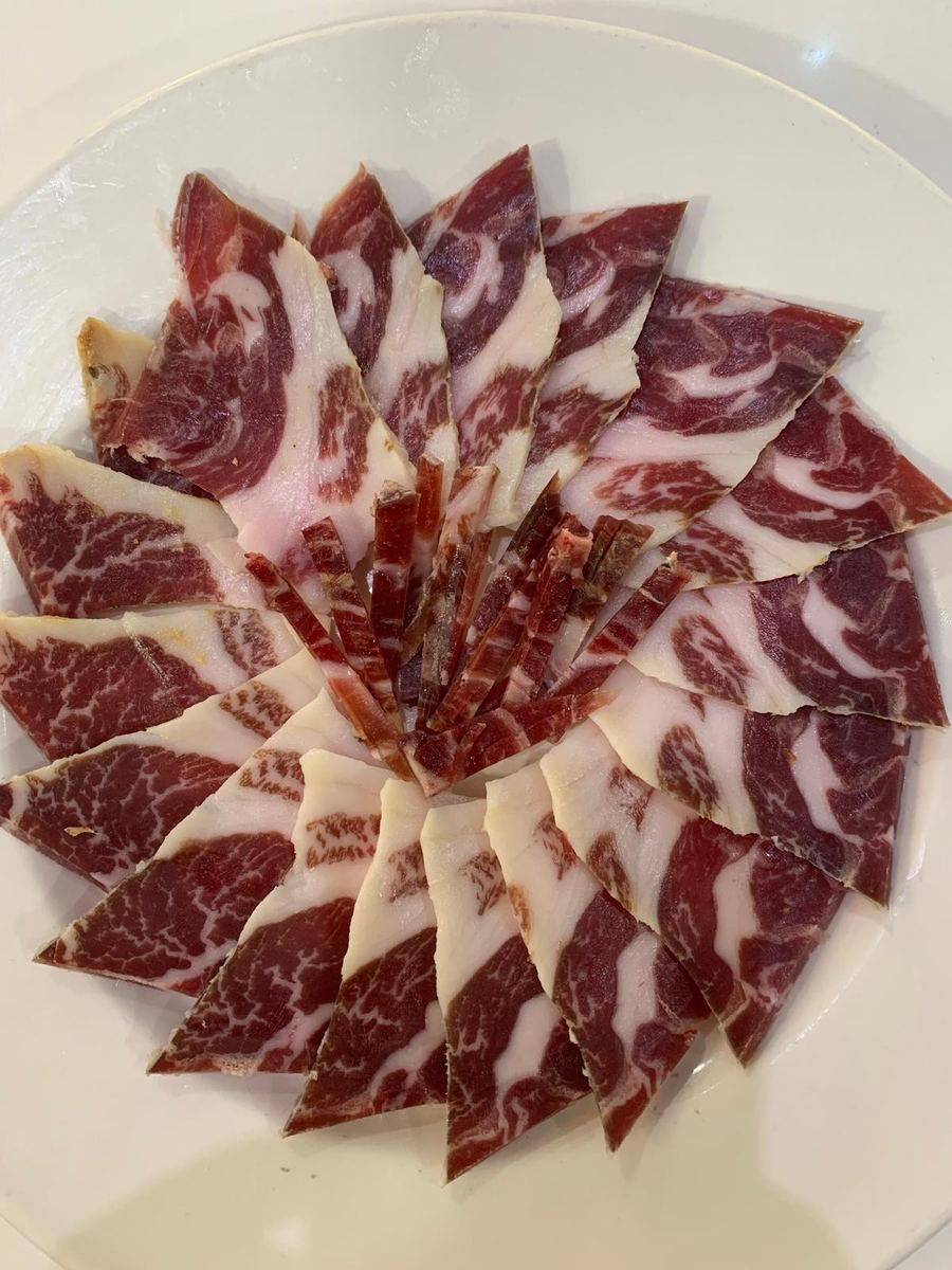 Plato de jamón ibérico cortado a mano con presentación en estrella sobre fondo claro