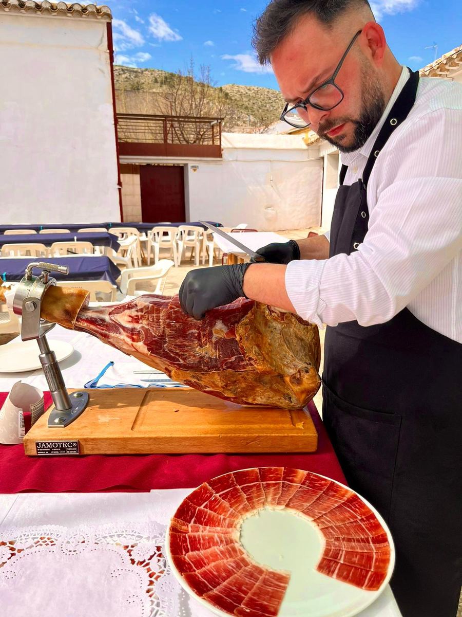 Adrián cortando un jamón ibérico al aire libre en un evento privado en la región de Murcia